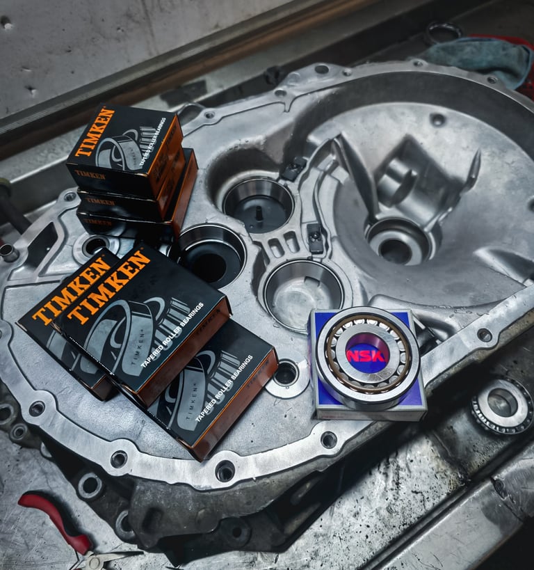 Timken and NSK tapered roller bearings sitting on a clean aluminium transmission housing.