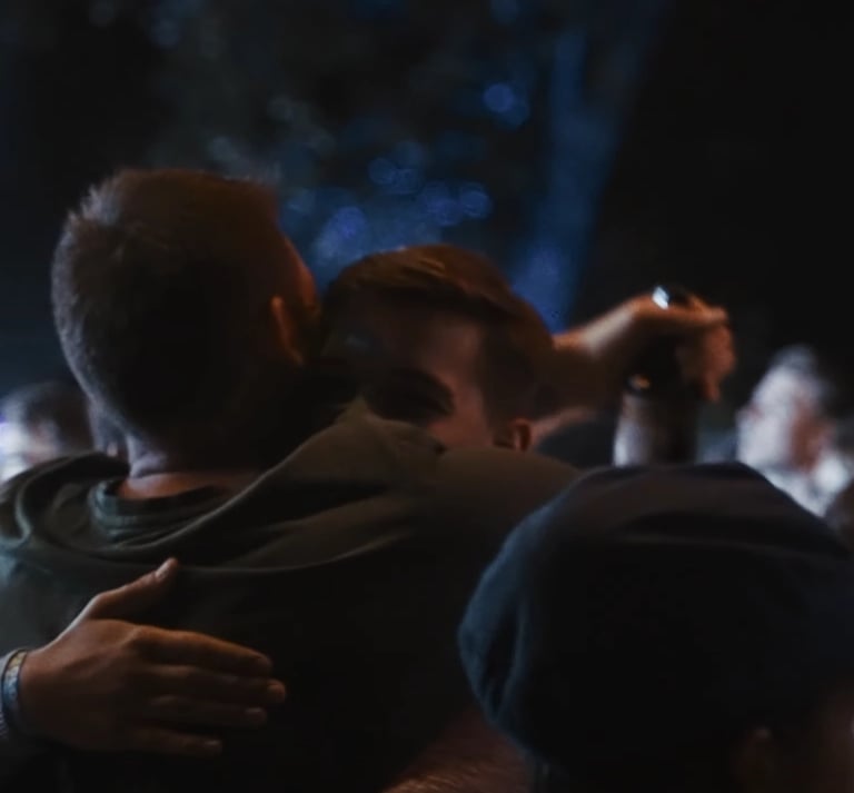 Two friends hugging and enjoying a night out at a crowded music festival or outdoor concert.