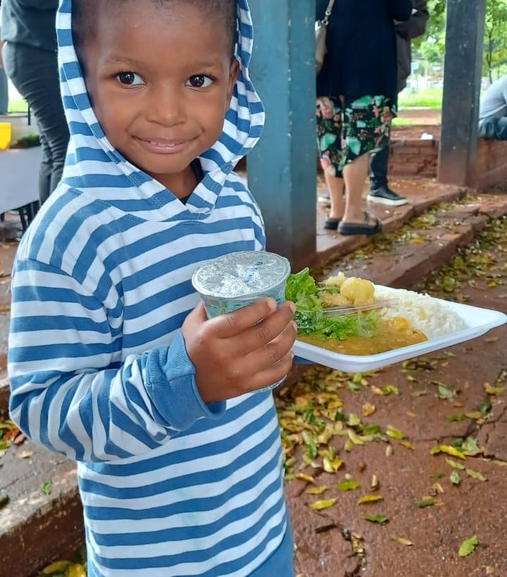 Um menino segurando seu prato de comida