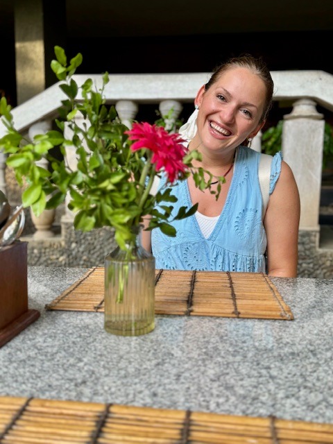 Alena Booth smiling next to red flowers in india