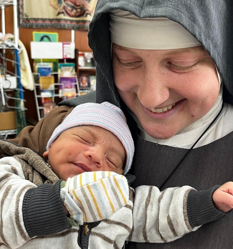 Franciscan Daughter of Mary holding a baby at the Rose Garden Home Mission