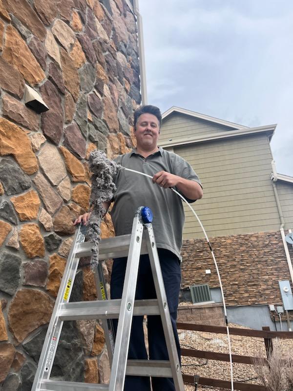 After a King Organic Dryer vent cleaning man standing on ladder holds large pile of lint