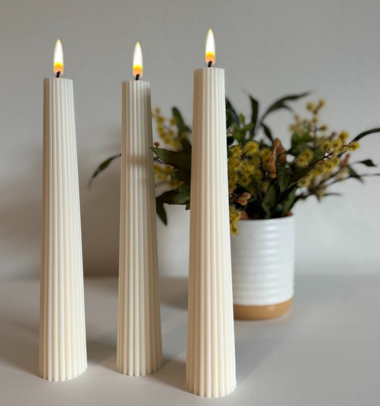 Three pillar candles lit and a flower vase