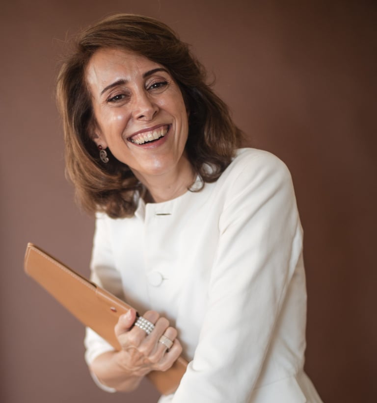 a female life coach in a white jacket holding a brown clutch