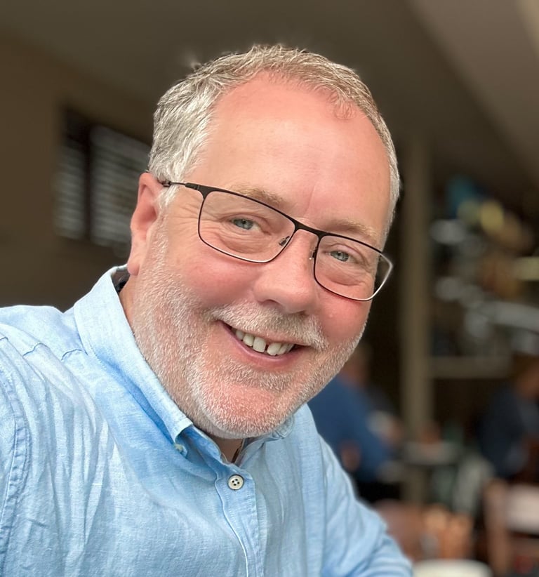 photograph of Rupert Kirby, photographer. Casual blue shirt, glasses and very handsom