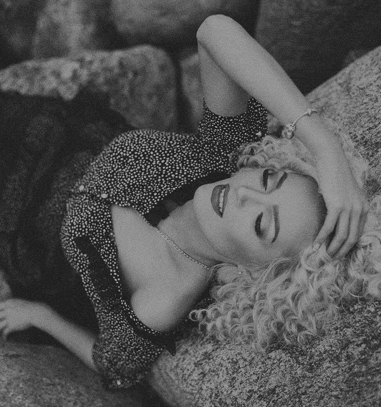 a woman laying on a rock in a black and white photo