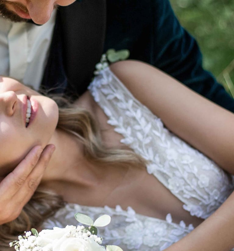 a bride and groom are sitting on the grass