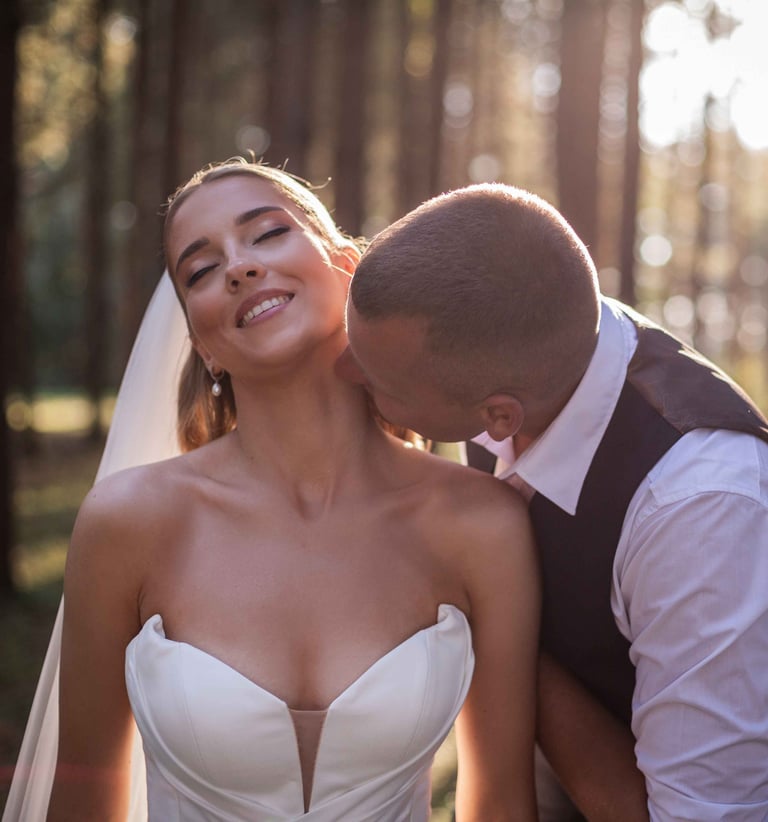 a bride and groom kissing in the woods