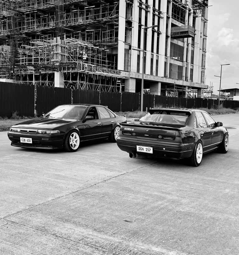 Nissan A31 cars parked on the road with scaffolding in the background