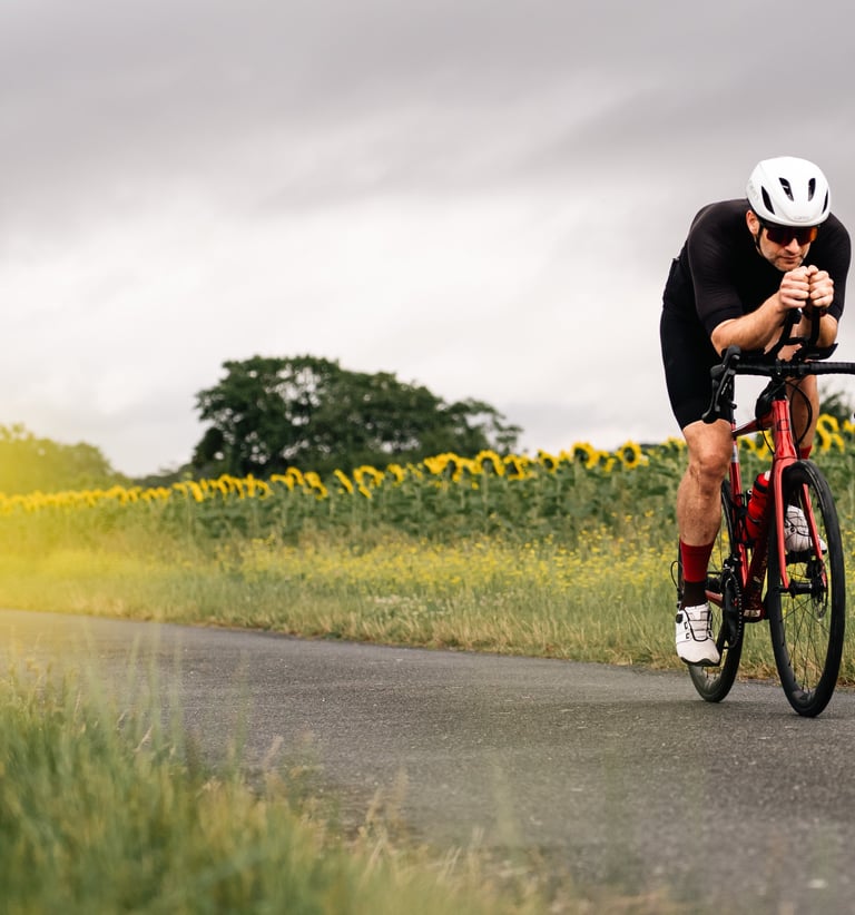 Cycliste en plein effort sur une route de campagne, bouton d’or flou au premier plan, photographie d