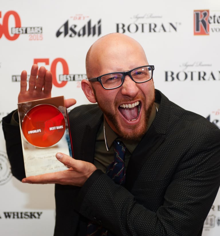 a man with a beard and glasses holding an award, he is very excited about winning