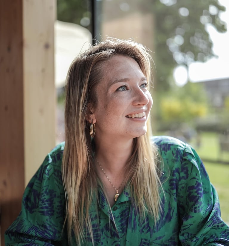 Een vrouw zit aan een tafel met een kop koffie.