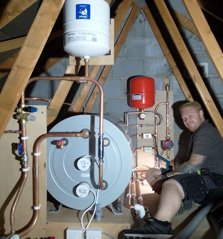 Professional plumber installing a thermal store water tank and expansion vessel in a home attic.
