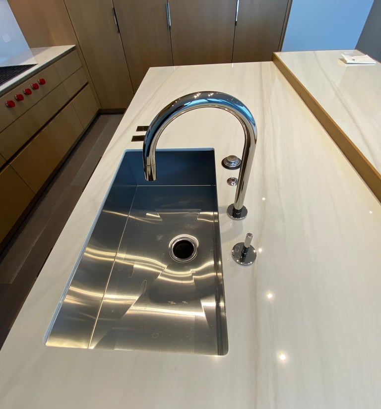 Modern stainless steel undermount kitchen sink on white marble countertop with chrome gooseneck faucet.