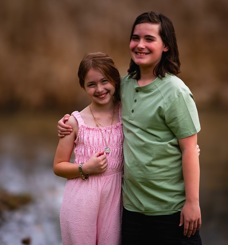 Two happy siblings smiling together outdoors, one wearing a pink jumpsuit, Athens, Ohio Burr Oak 
