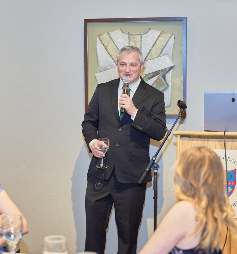 A man in a suit giving a speech toasting at a 50th anniversary party at Grace Episcopal Church.