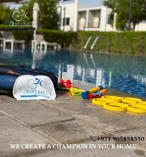 Swimming gear including a branded swim cap and colorful training toys by a luxury outdoor pool.