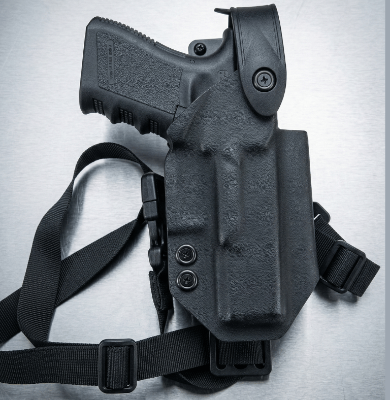 Black tactical Kydex holster with adjustable thigh strap holding a semi-automatic handgun.