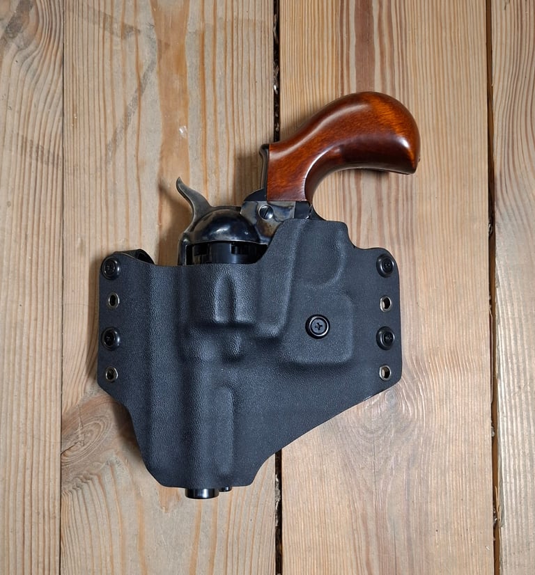 A classic revolver with a wooden grip secured in a black Kydex holster on a wooden background.