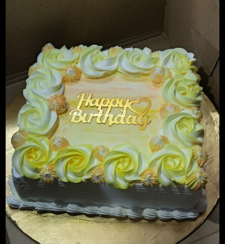 "Freshly baked pineapple birthday cake decorated with whipped cream, pineapple slices, and cherries,