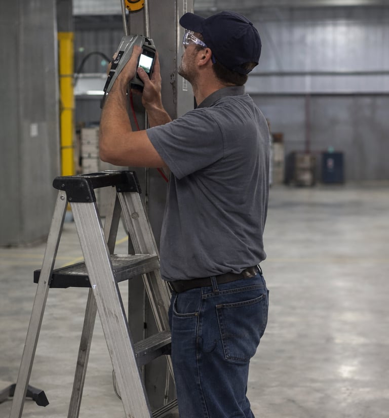 a man in a gray shirt near a ladder inspecting a maintenance tool