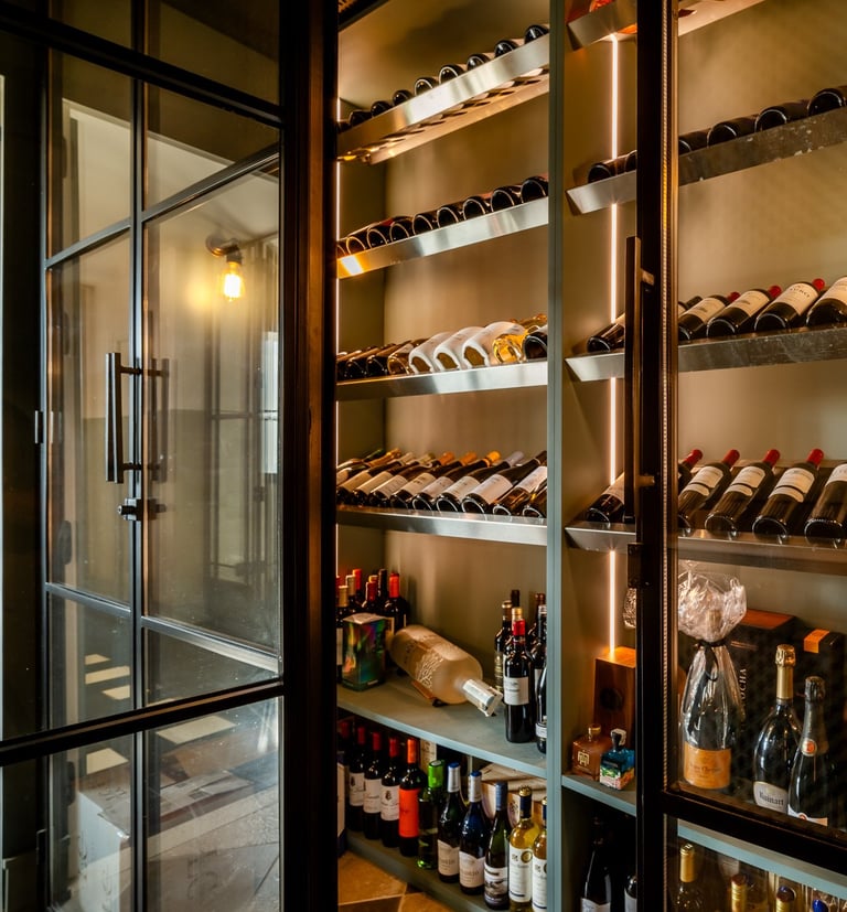 Contemporary wine cellar at Villa La Gratitud with glass doors, backlit shelves, and wine collection