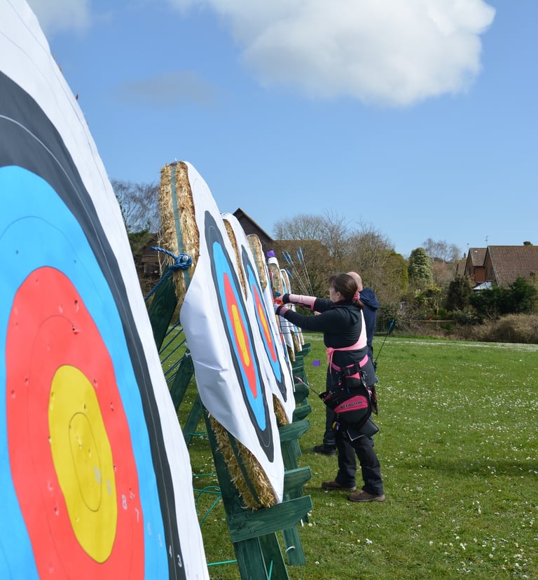 a man and woman are standing in front of an archery target
