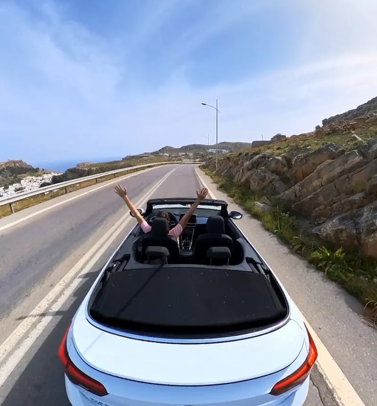 a man driving a convertible car down a road