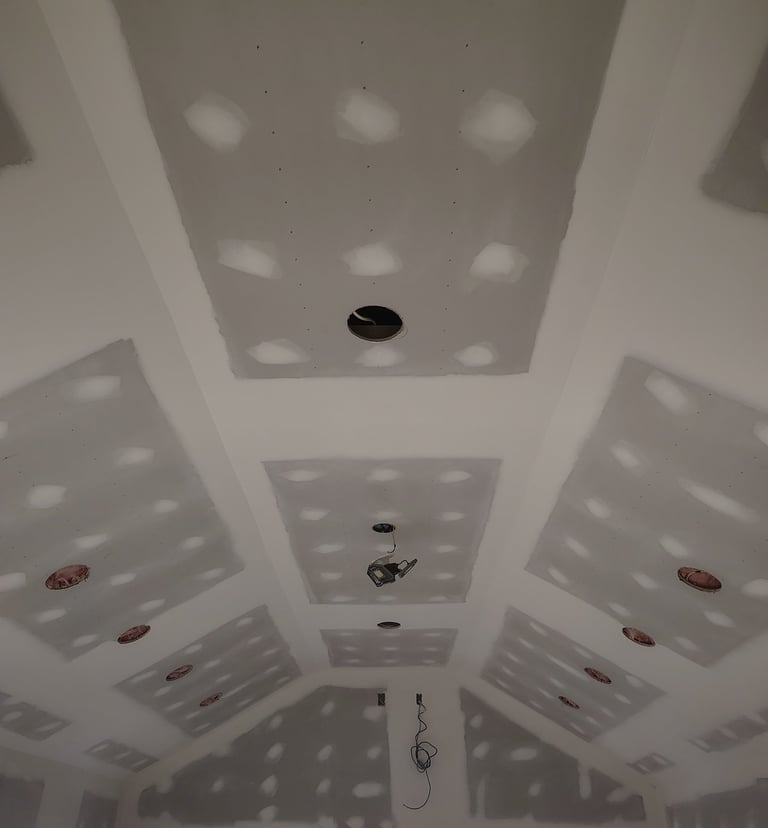 Vaulted tray ceiling with finished drywall and joint compound mudding during home construction.