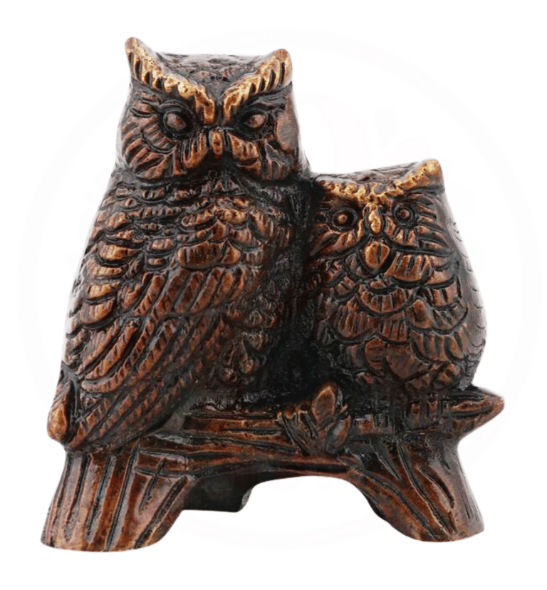 a pair of brass owls sitting on a tree branch