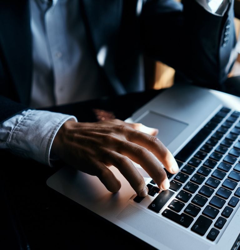 a man in a suit and tie is typing on a laptop