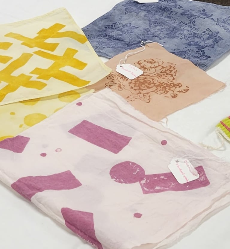 Block-print dyed fabrics of pink, yellow, brown, and blue.