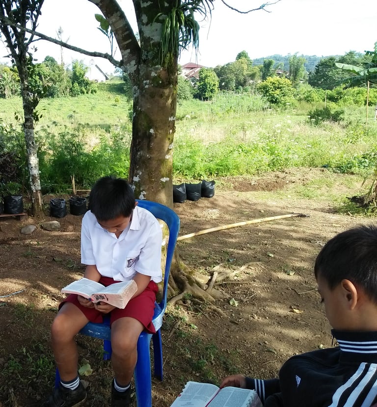 a group of children sitting in chairs in a circle reading the Bible
