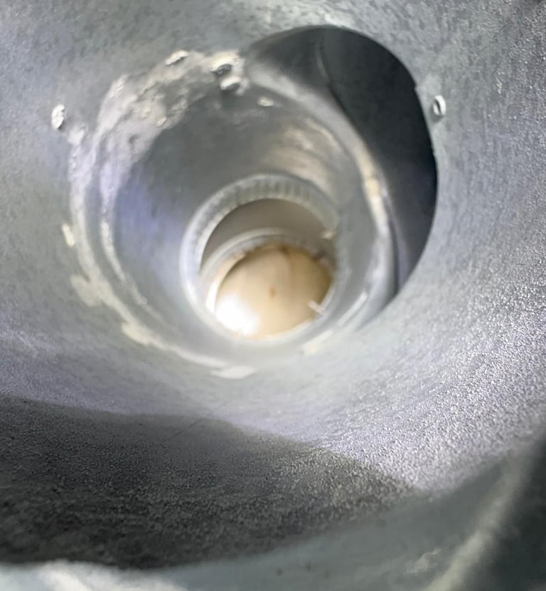 A view from inside a dirty and worn metal chimney flue, highlighting the need for a professional cleaning and inspection by R