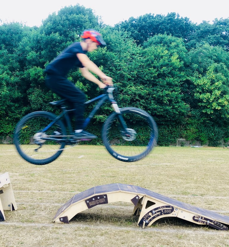 a man jumping a bicycle off some ramps in a field
