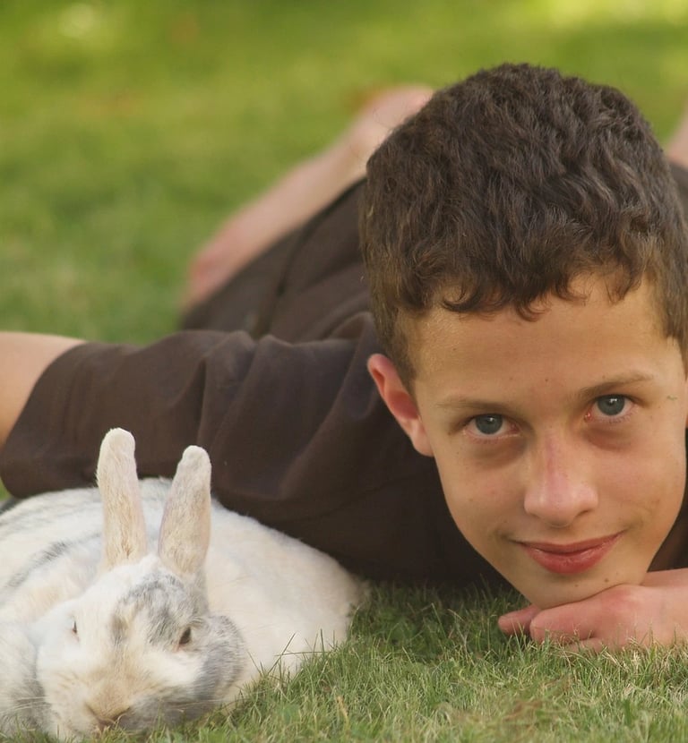 un garçon avec un lapin blanc dans l'herbe