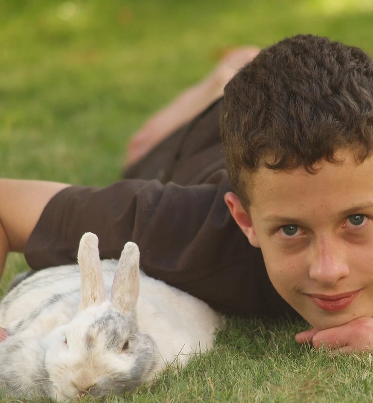 un garçon avec un lapin blanc dans l'herbe