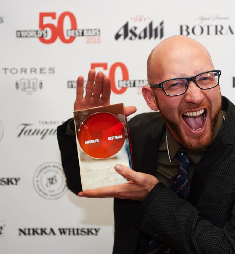 a man with a beard and glasses holding an award, he is very excited about winning