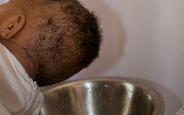 un prêtre baptise un bébé pour son bapteme