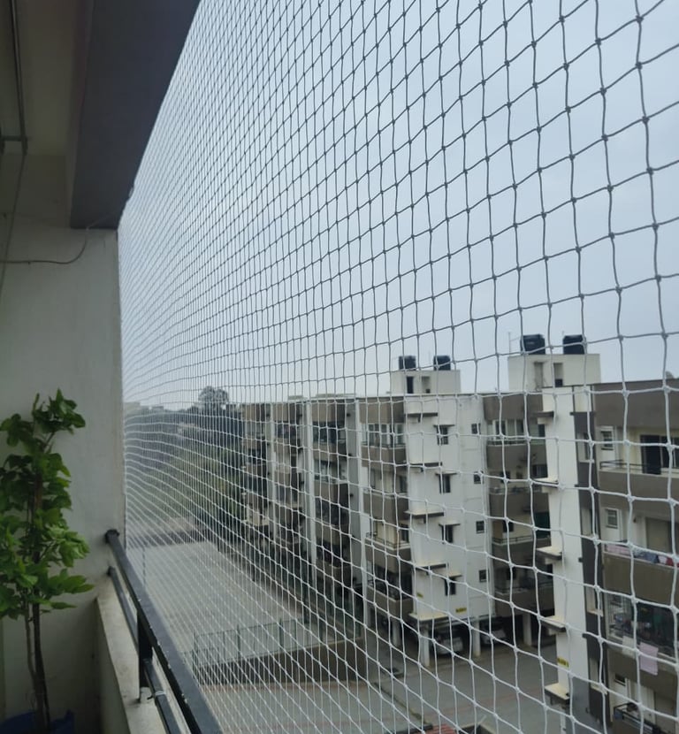 Wide shot showing a balcony fully secured with a sturdy safety net against a bright blue sky.