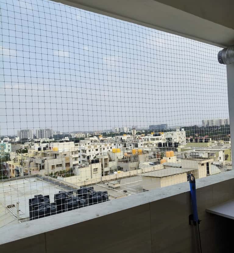 Installation team fitting pigeon nets on a large sarja window in Marathahalli.