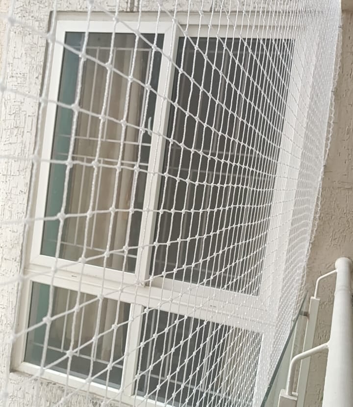 Side view of a balcony safety net with a child playing safely behind it