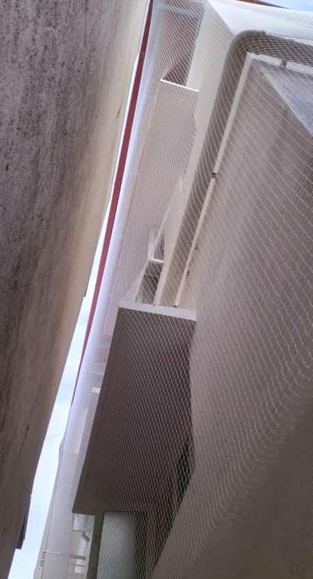 Technician from Arjilli Enterprises carefully fitting a protective net inside a duct area.