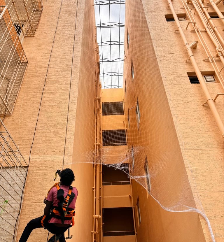 Technician from Arjilli Enterprises securing a pigeon net frame on a rooftop.