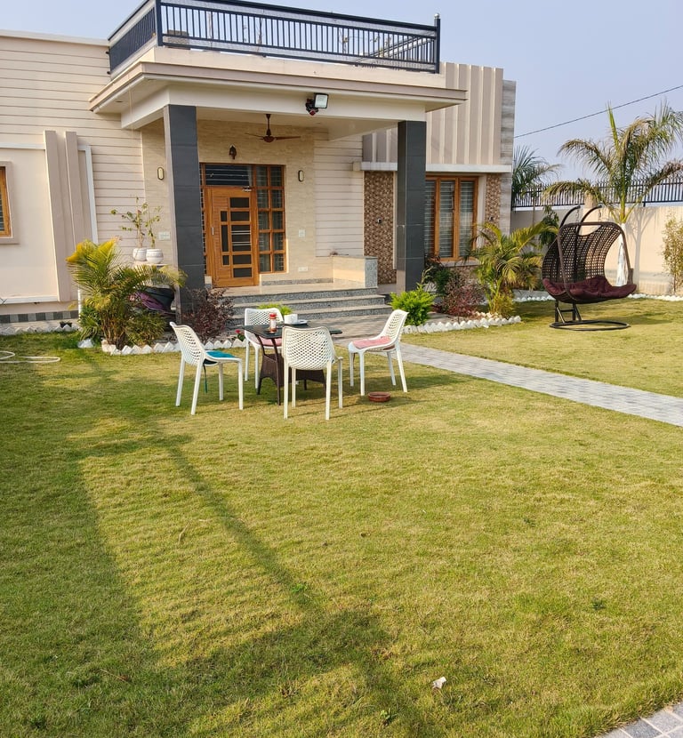 Modern luxury PG exterior with a spacious green lawn, patio furniture, and hanging swing chair.