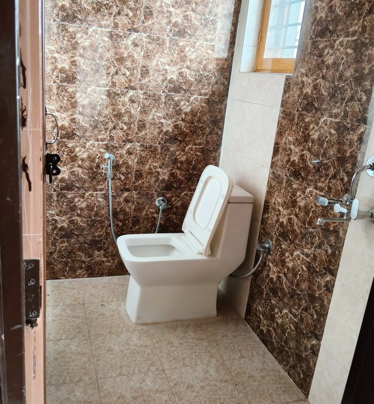 Modern bathroom featuring a white ceramic toilet and elegant brown marble wall tiles.