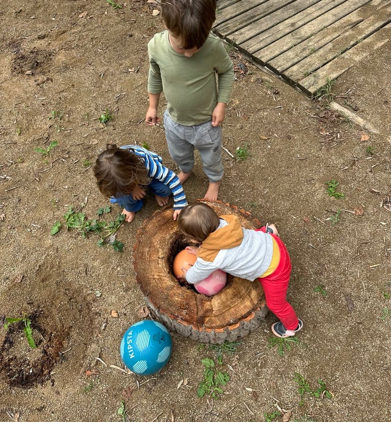 Infants jugant a l’exterior amb troncs i pilotes