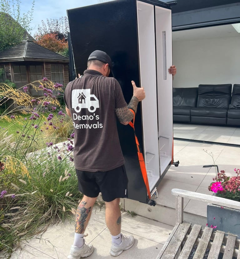 a man in a black shirt is moving a refrigerator