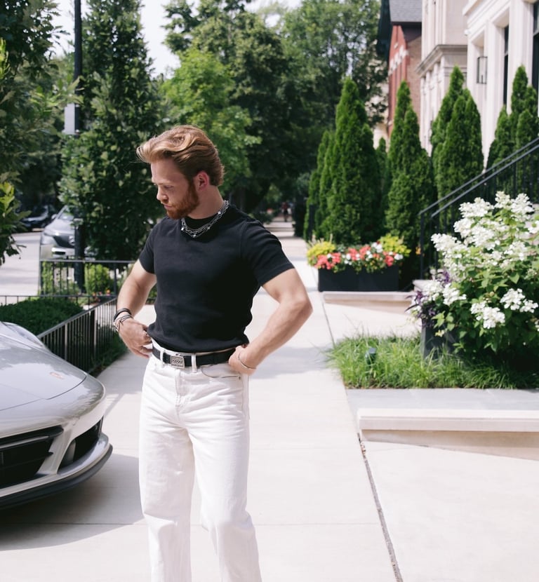 a man standing on a sidewalk with a car parked in front of him