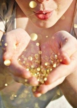 femme soufflant sur des paillettes dorées posées sur ses mains